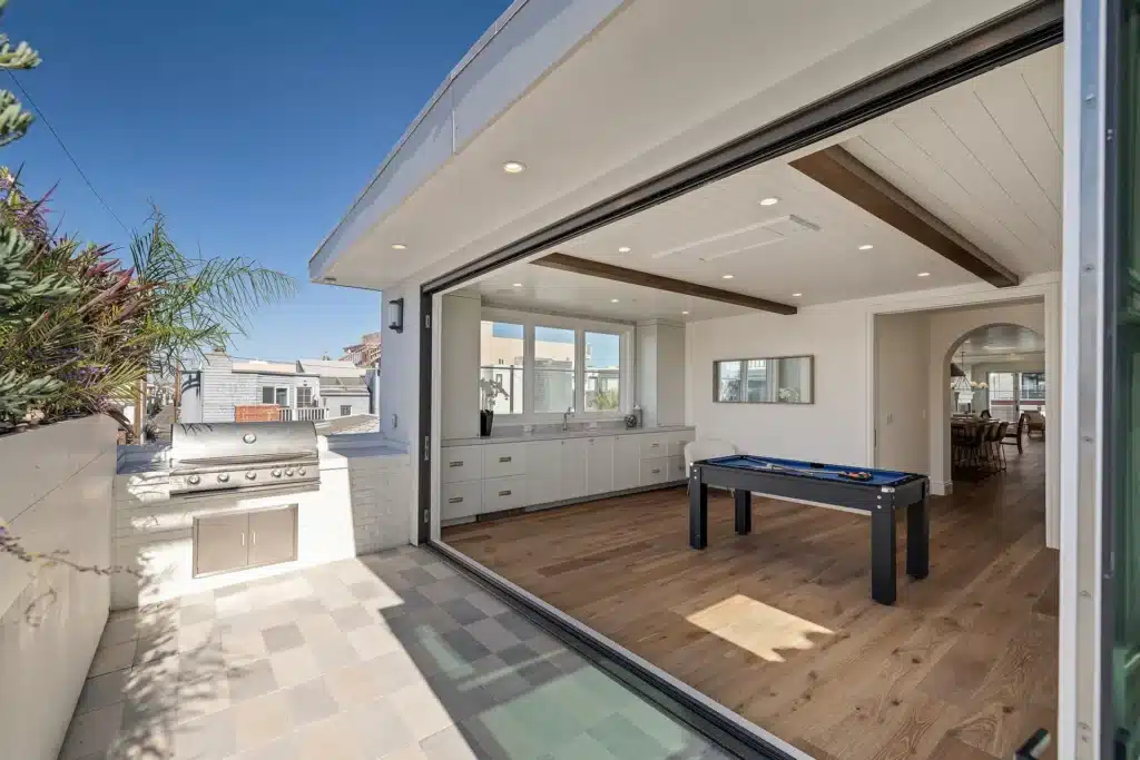 Game room opening to the patio through a full-width sliding wall, with a built-in grill