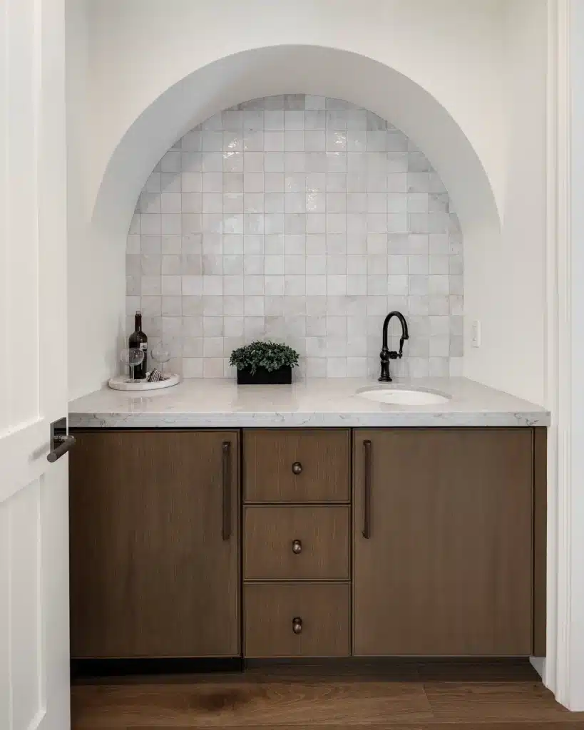 Arched zellige alcove above a stone-topped vanity with dark oak cabinetry