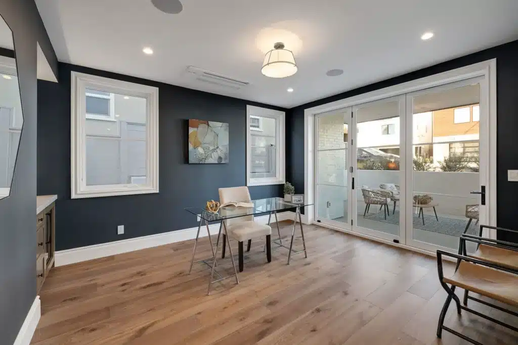 Office with navy walls, oak flooring and sliding doors to a private balcony